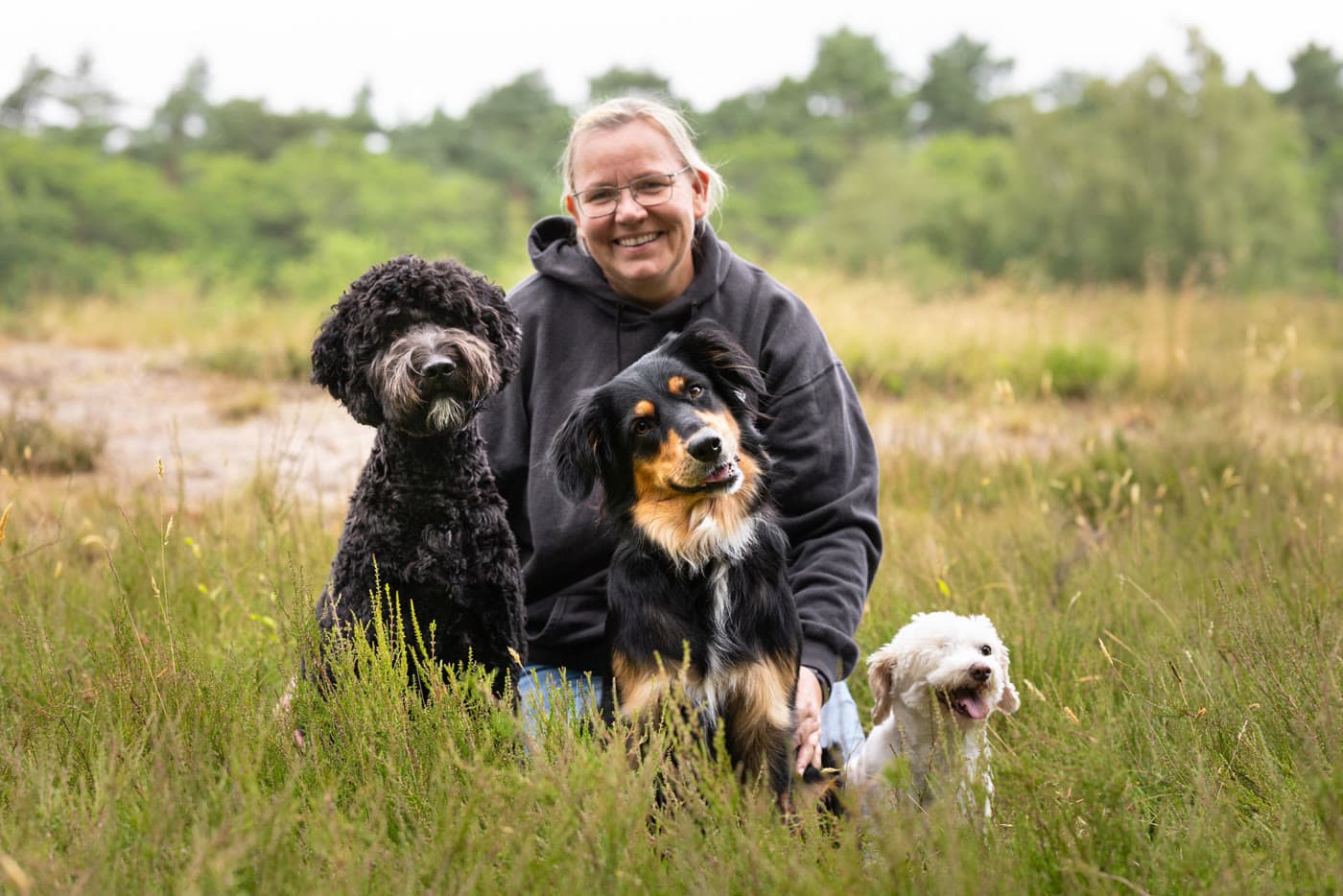 Martina Garske kniet mit ihren drei Hunden in der Heide